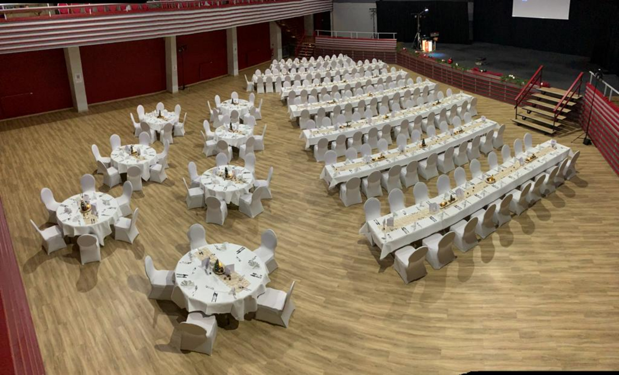 Großer Bankettsaal in der Kronenhalle mit runden und langen Tischen, weiß gedeckt, Holzfußboden, rote Wände, Bühne am Raumende.