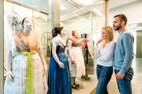 Ein Mann und eine Frau betrachten sorbische Tracht im Museum