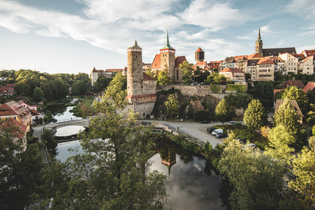 Historischer Blick auf Bautzen mit der Alten Wasserkunst, mittelalterlichen Gebäuden, Fluss, Brücke und grüner Umgebung.